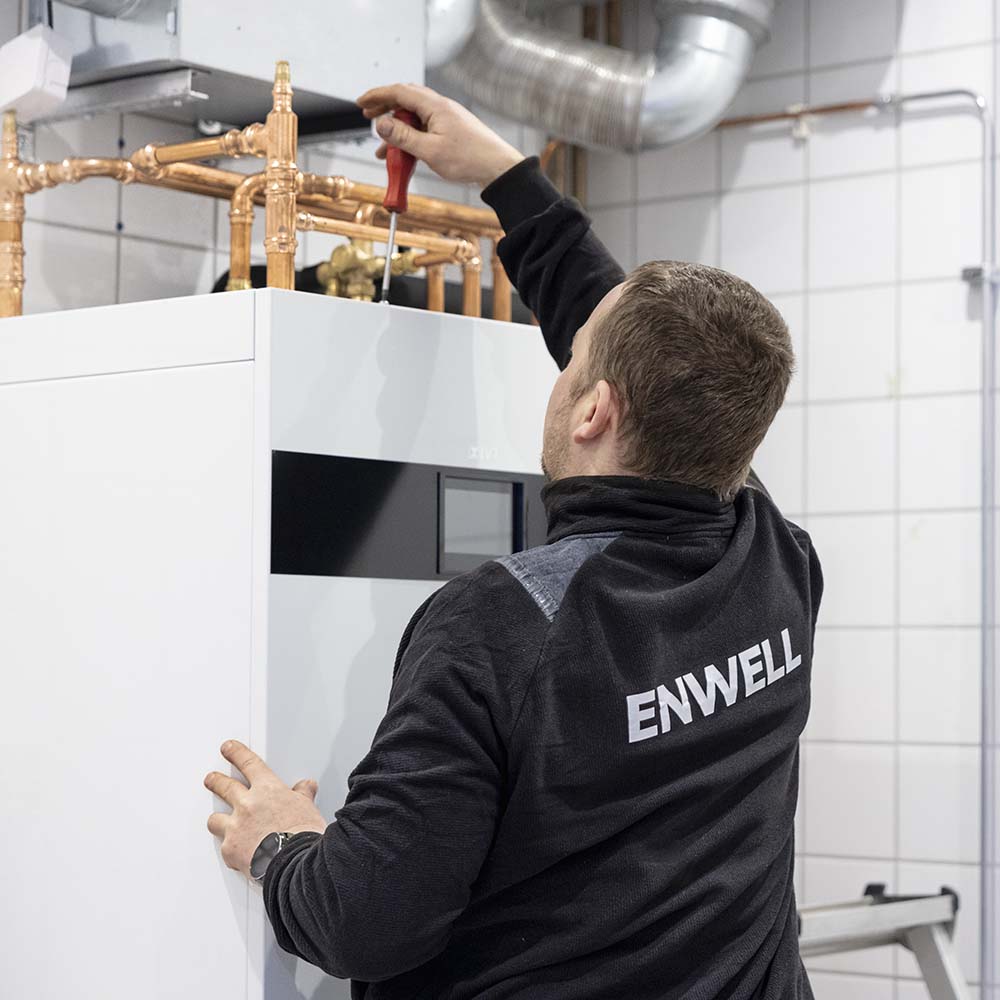 Person håller i en skruvmejsel och installerar en jordvärmepump från IVT