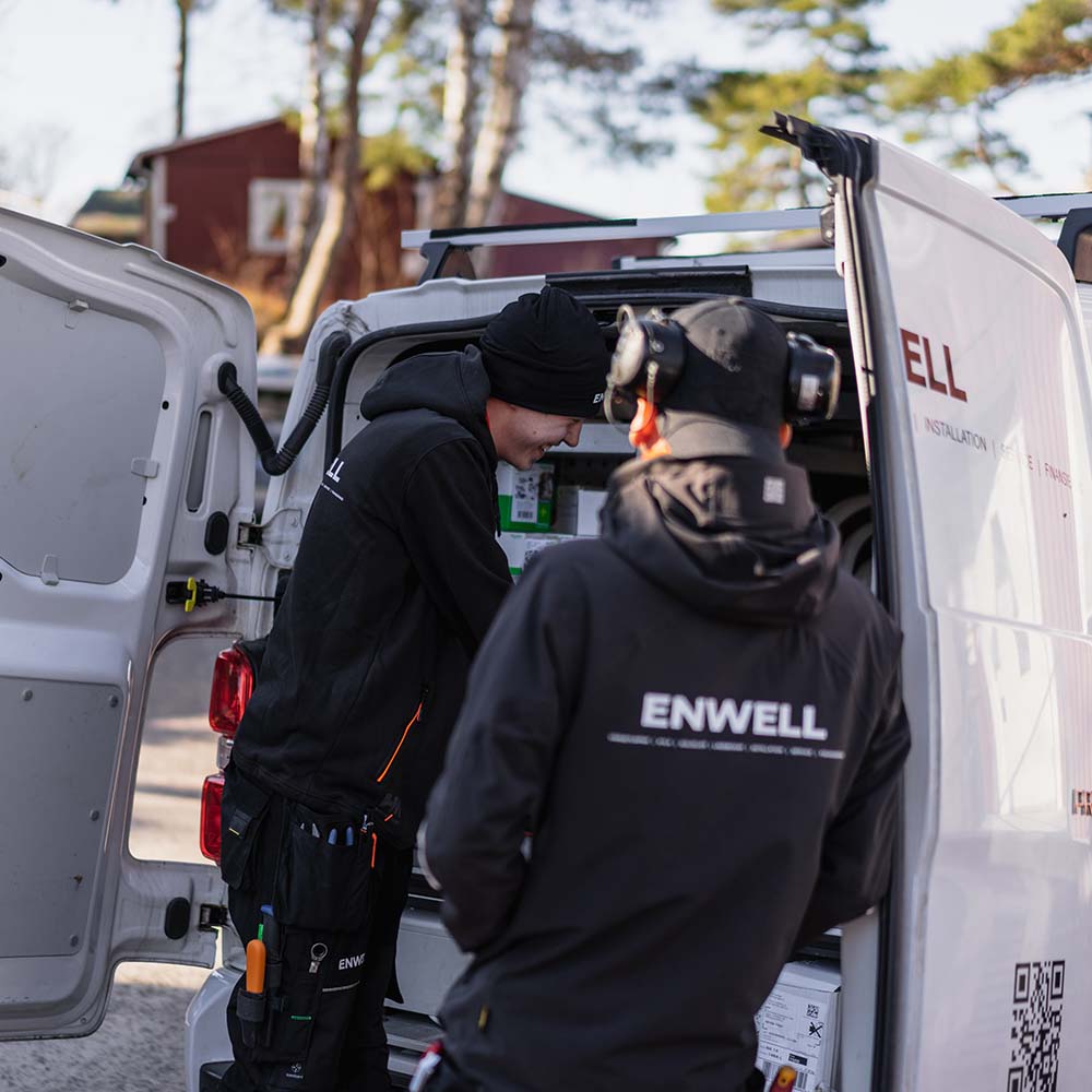 Två tekniker står bakom vit skåpbil med öppnade dörrar