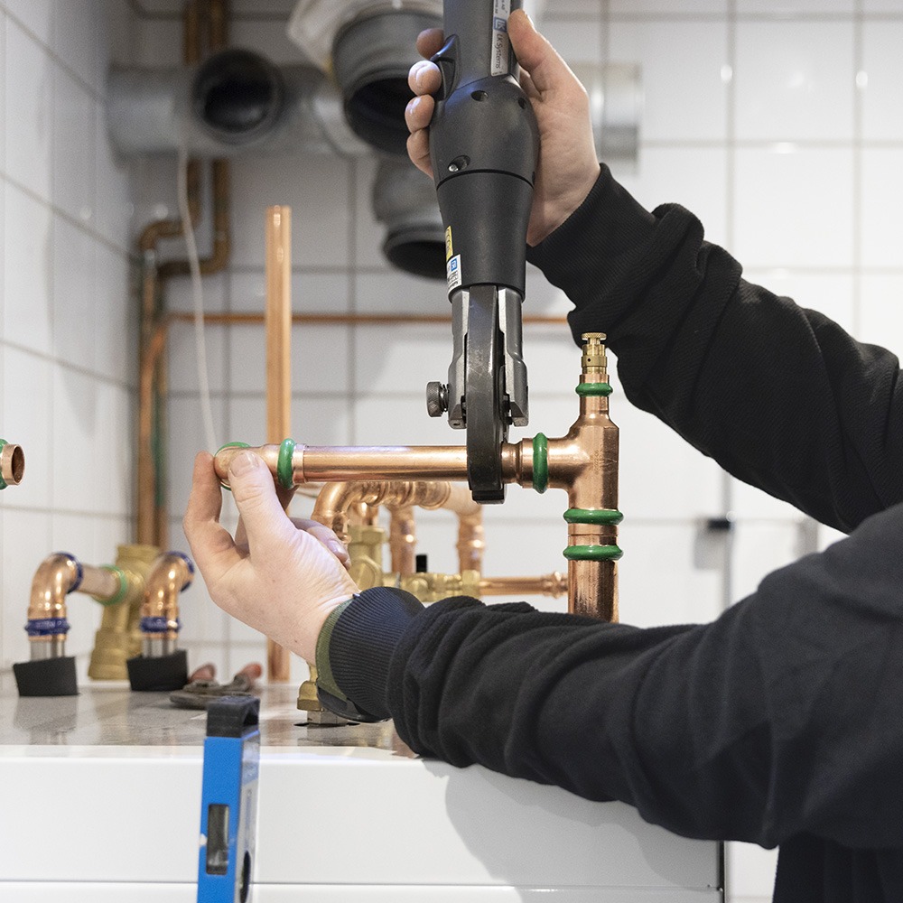 Person som håller i ett verktyg och installerar en värmepump