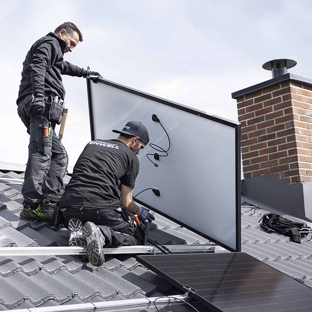 Två personer på tegeltak som installerar solceller