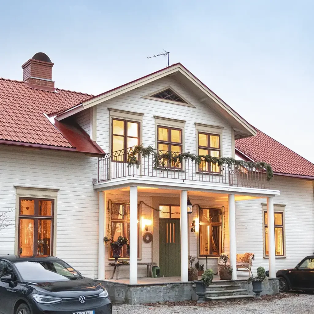 Vit villa med rött tak, svart parkering på framsidan